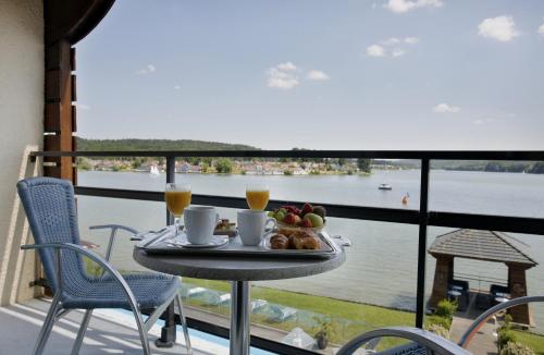 a table with a tray of food and drinks on a balcony at Hôtel du Golf de l'Ailette, The Originals Relais in Chamouille