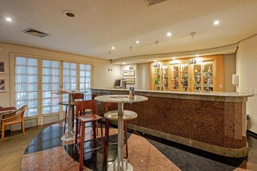 a bar in a restaurant with stools and tables at Rede Andrade Braz in Curitiba