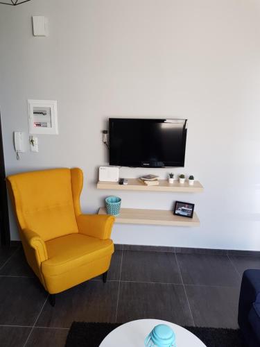 a living room with a yellow chair and a tv at City Life Apartments #1 in Ioannina