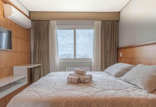 ein Schlafzimmer mit einem Bett, auf dem ein Teddybär liegt in der Unterkunft Via Florida Luxo II - 303 in Gramado