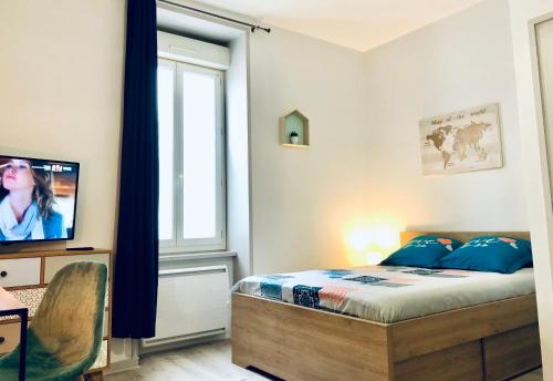 a bedroom with a bed and a tv and a window at Studio Cosy Family in Roanne