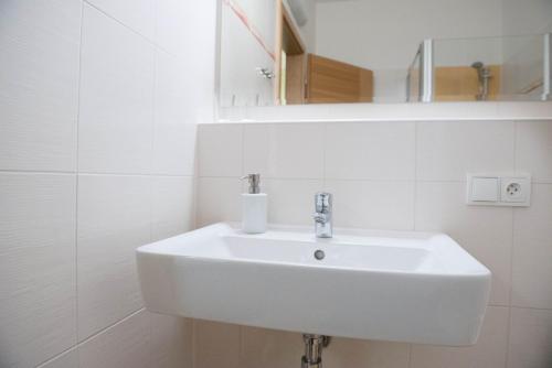 a white sink in a white tiled bathroom at Penzion Rondo in Bystřice pod Hostýnem