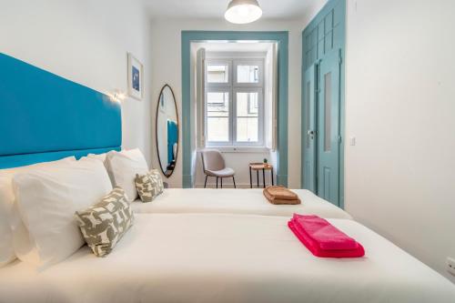 Un dormitorio con una gran cama blanca con una toalla roja. en LV Premier Baixa DO en Lisboa