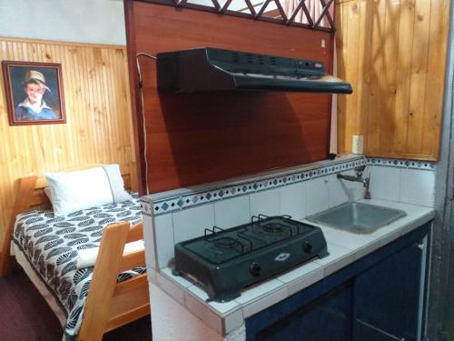 uma cozinha com um fogão e um lavatório ao lado de uma cama em Casa Posada Amelia em Bogotá