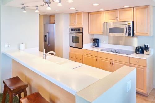 a kitchen with wooden cabinets and a white counter top at Aston Kaanapali Shores in Lahaina