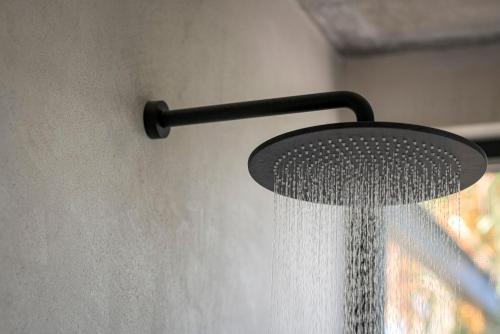 a shower head with water coming out of it at OPENNESS House by the sea in Marathi