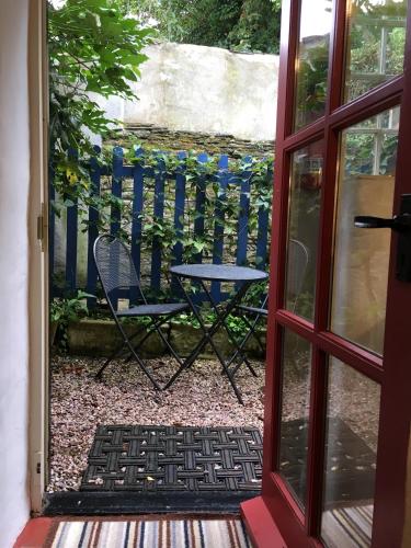 an open door to a patio with a table and chairs at Charming Devon Cottage near Quay-Rain Shower, Restaurants & Free Parking in Kingsbridge