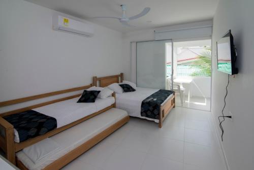 a bedroom with two beds and a tv and a balcony at Habitacion Coveñitas 203 in Coveñas
