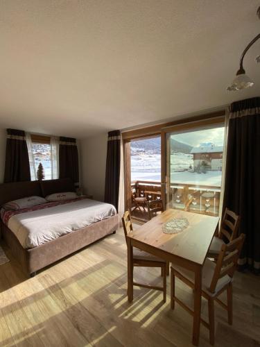 a bedroom with a bed and a table and a view at Mont Chalet Apartaments in Livigno