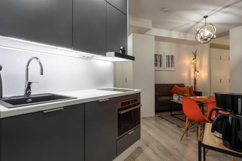 una cocina con armarios negros, fregadero y mesa en Tuomas´luxurious suites, Koivu en Rovaniemi