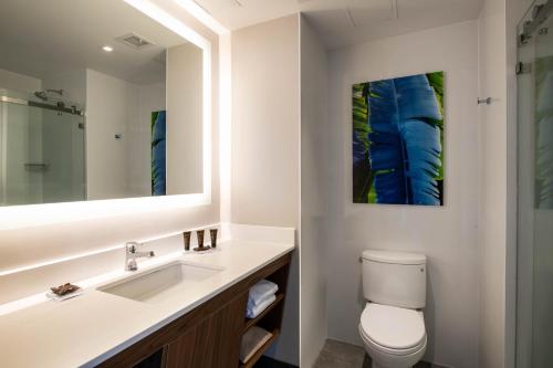 a bathroom with a sink and a toilet and a mirror at Wingate by Wyndham Long Island City in Queens