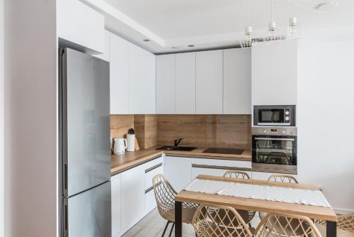 a kitchen with white cabinets and a wooden table and chairs at Apartament Koja in Giżycko