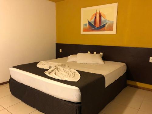 a bedroom with a large bed with a painting on the wall at Saint Patrick Praia Hotel in Maceió