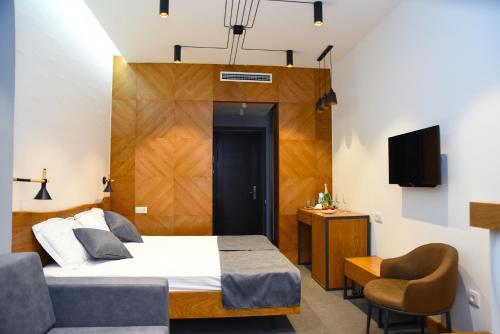 1 dormitorio con 1 cama, 1 silla y TV en R&R Hotel en Ereván