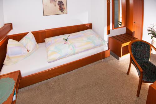 a small bedroom with a bed and a chair at Pension Cafe Suzette in Gotha
