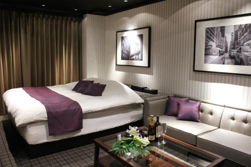 北九州市にあるHotel LOVE MODERNのベッドとソファ付きのホテルルーム