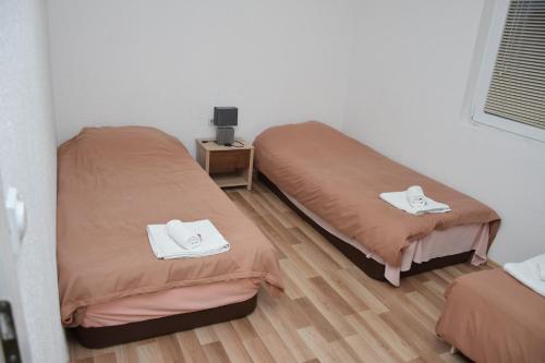 two twin beds in a room with a wooden floor at Markos Towers Apartments in Prilep
