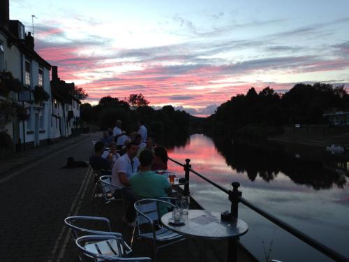 a group of people sitting at a table near a river at The Mug House Inn in Bewdley