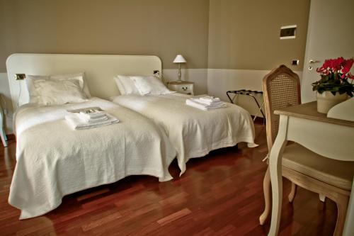 a bedroom with two beds with white sheets and a piano at Borgo Manzoni - Charming House in Rozzano
