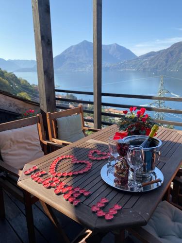a wooden table with roses and glasses on a balcony at The Cozy Nest - Bellano in Bellano