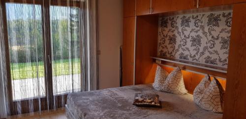 ein Schlafzimmer mit einem Bett und einem großen Fenster in der Unterkunft Ferienwohnungen Pirker in Drobollach am Faakersee
