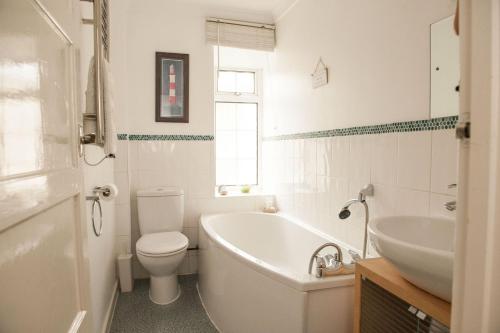 a bathroom with a tub and a toilet and a sink at Teal House in Lyme Regis