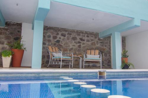 a swimming pool with two chairs and a table at Hotel Pura Chacala in Chacala