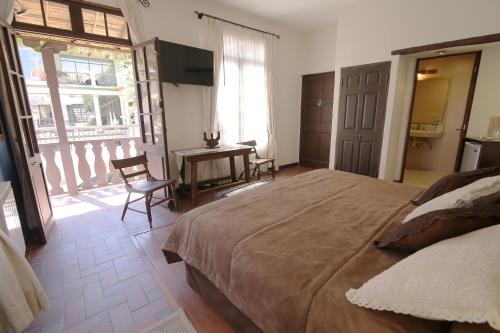 
a room with a bed, chair, table and window at Mi Pueblo Samary Hotel Boutique in Sucre
