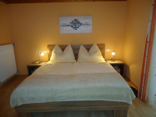 a bedroom with a large white bed with two lamps at Haus Zerza in Dorfgastein