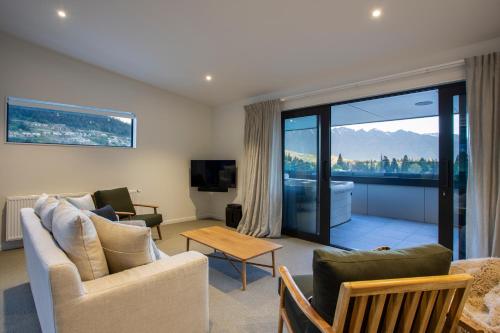 a living room with a couch and chairs and a tv at Whakarire by Sotheby's Luxury Rental Homes in Queenstown