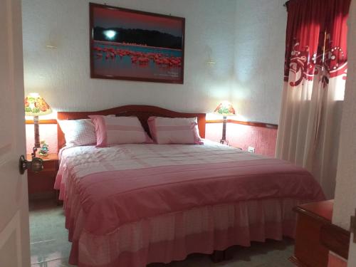 a bedroom with a large bed with two lamps at Casa Palagui Colonial in Valladolid