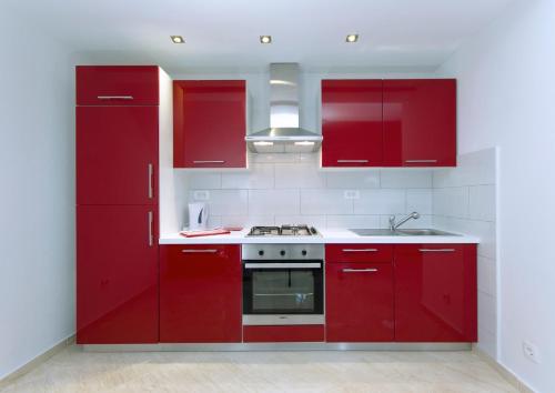 cocina con armarios rojos y fogones en City Apartments Nada, en Makarska