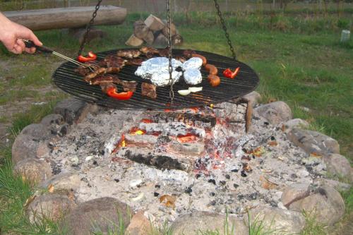 a person cooking food on a grill over a fire at Dom Wczasowy Pięciu Pomostów in Czaplinek