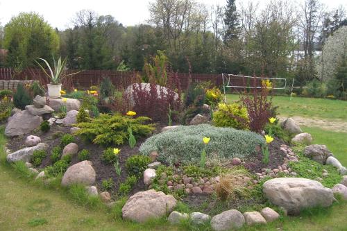 a garden with rocks and flowers in a yard at Dom Wczasowy Pięciu Pomostów in Czaplinek