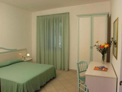 a bedroom with a green bed and a table and a chair at Hotel Residence La Fortezza in San Lucido