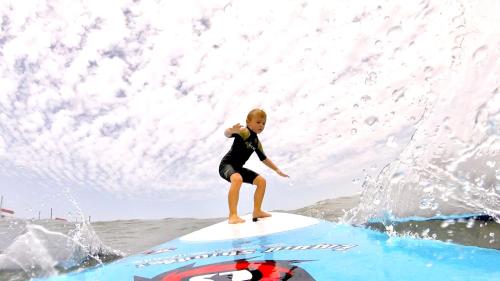 a young girl riding a wave on a surfboard in the ocean at Surf hostel My Friends in Huanchaco