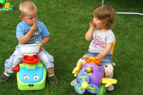 two young children sitting on the grass eating food at Dom Wczasowy Pięciu Pomostów in Czaplinek