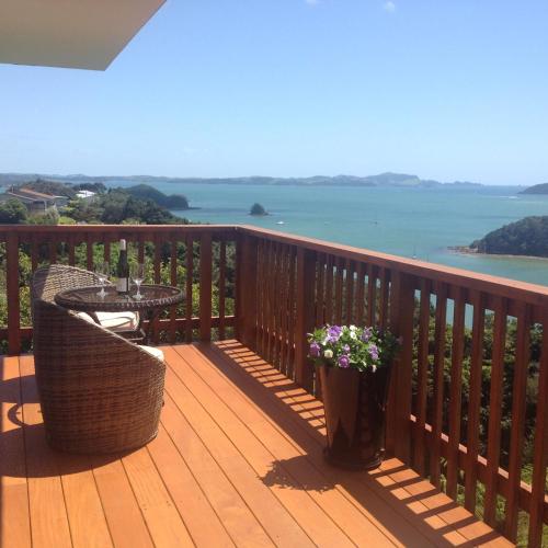 a wooden deck with a table and flowers on it at Panorama Heights Apartment in Paihia