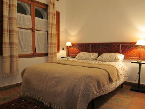 a bedroom with a large bed with two lamps at Hôtel Ras El Maa in Chefchaouene