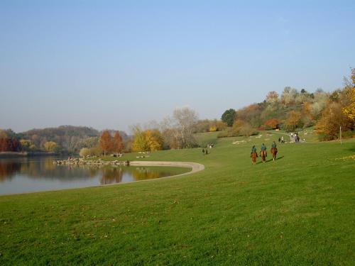 um grupo de pessoas caminhando em um parque ao lado de um lago em Gite Mella em La Courneuve