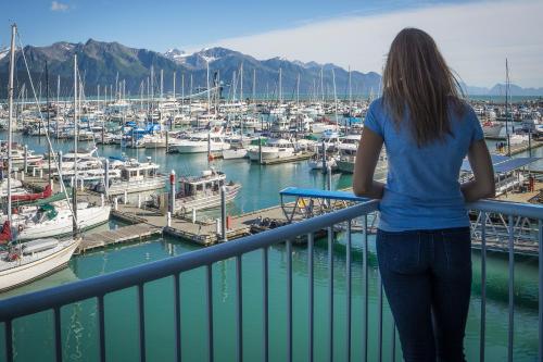 a woman standing on a balcony looking at a marina at Harbor 360 Hotel Seward in Seward
