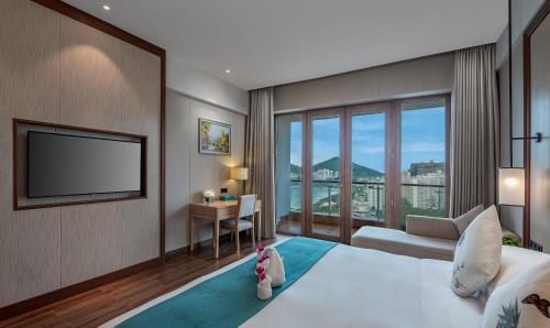 三亜市にあるSanya Dadonghai Hotelのベッドとテレビ付きのホテルルーム