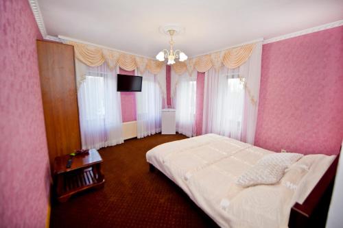 a bedroom with a white bed and pink walls at Fontan in Chornomorsk