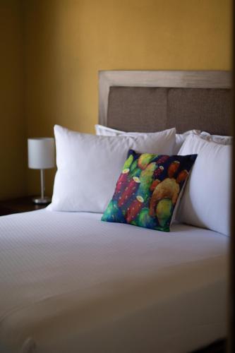 a bed with white pillows and a colorful pillow at Casa Flores Hotel & Spa in Atlixco