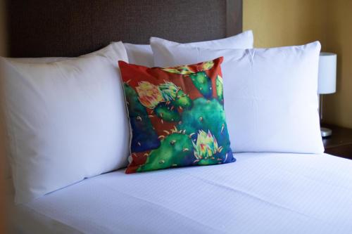 a bed with white pillows and a colorful pillow at Casa Flores Hotel & Spa in Atlixco