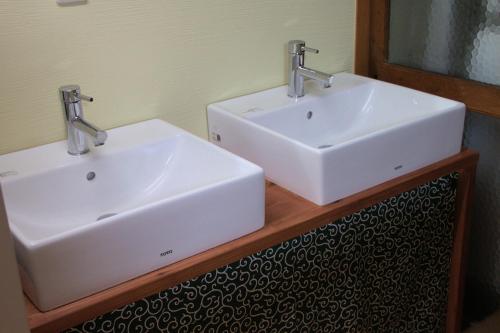 two white sinks on a wooden counter in a bathroom at Guest House Hitsujian in Kyoto