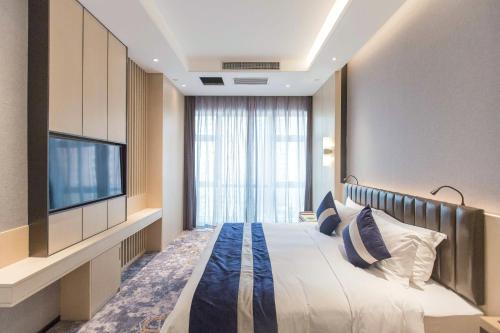 a hotel room with a bed and a flat screen tv at Chongqing Liyuan Hotel in Chongqing