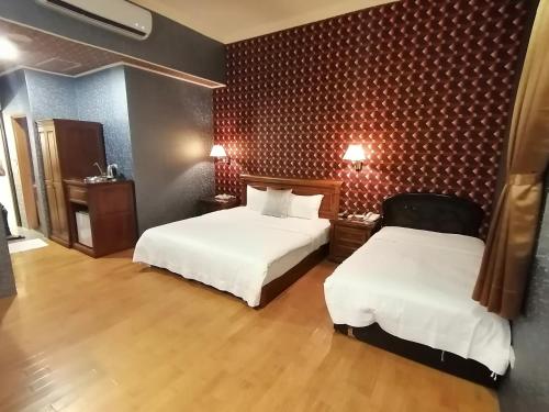 a hotel room with two beds with white sheets at Di Bao Motel in Ji'an