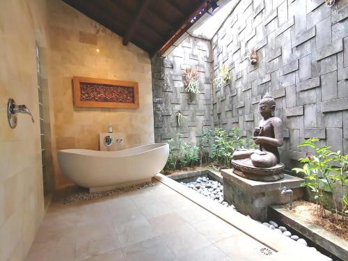 uma casa de banho com banheira ao lado de uma estátua em Ubud Bungalow em Ubud