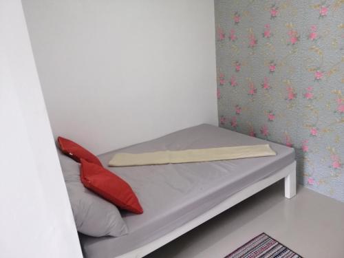 uma pequena cama com almofadas vermelhas num quarto em Katrina's Dorm em Tarlac